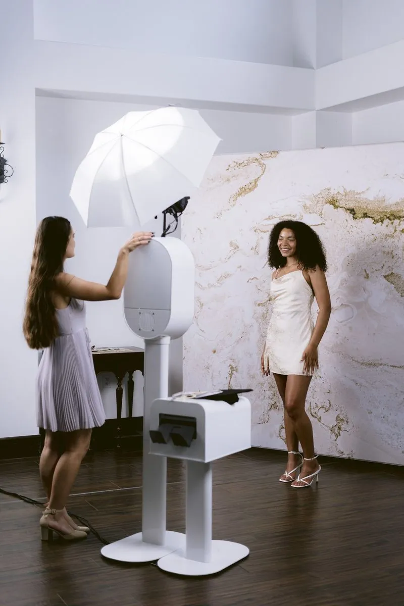 A guest using the booth touchscreen while another guest poses by a marble backdrop