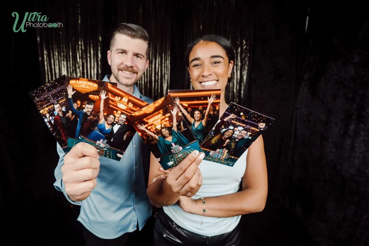 Two guests holding gold themed AI portrait prints in front of a dark backdrop
