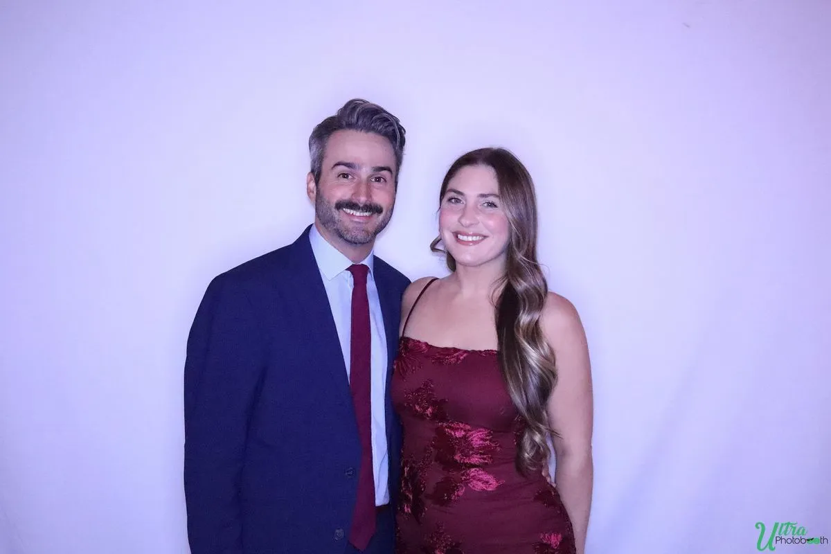 Two guests in evening attire posing against a softly lit backdrop at a gala