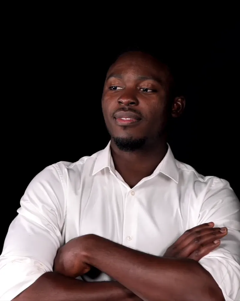 Professional in a white shirt with crossed arms against a black backdrop