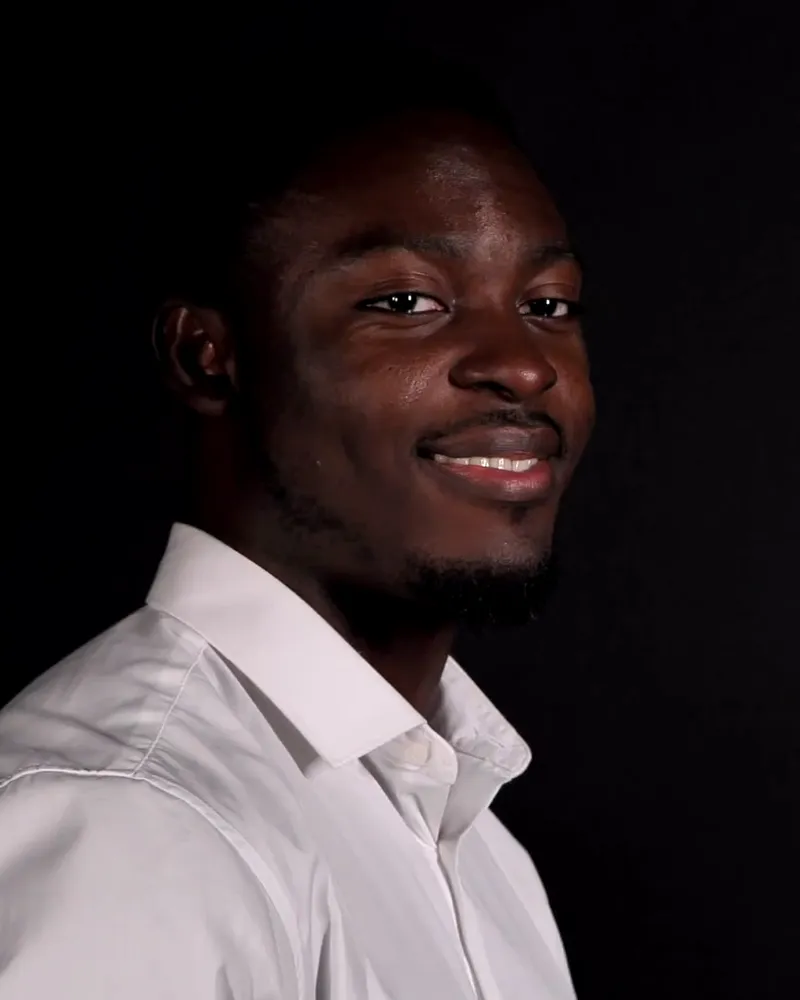 Smiling professional in a white shirt in a three-quarter pose against a black backdrop