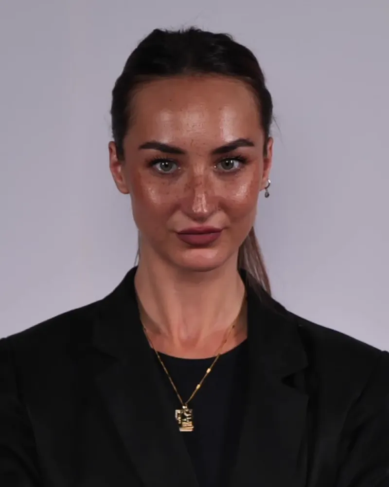 Professional in a black blazer facing the camera against a gray backdrop