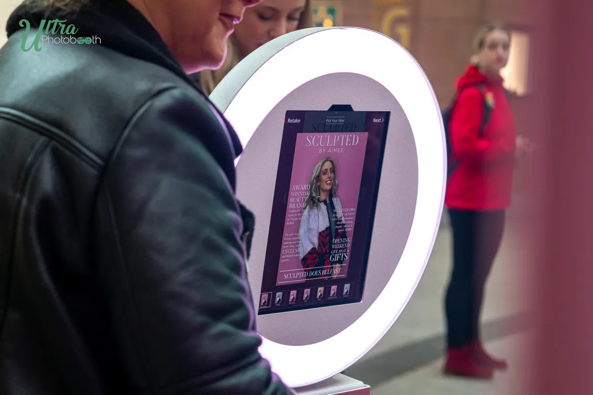 Attendant holding a circular roaming iPad booth while a guest uses its touchscreen