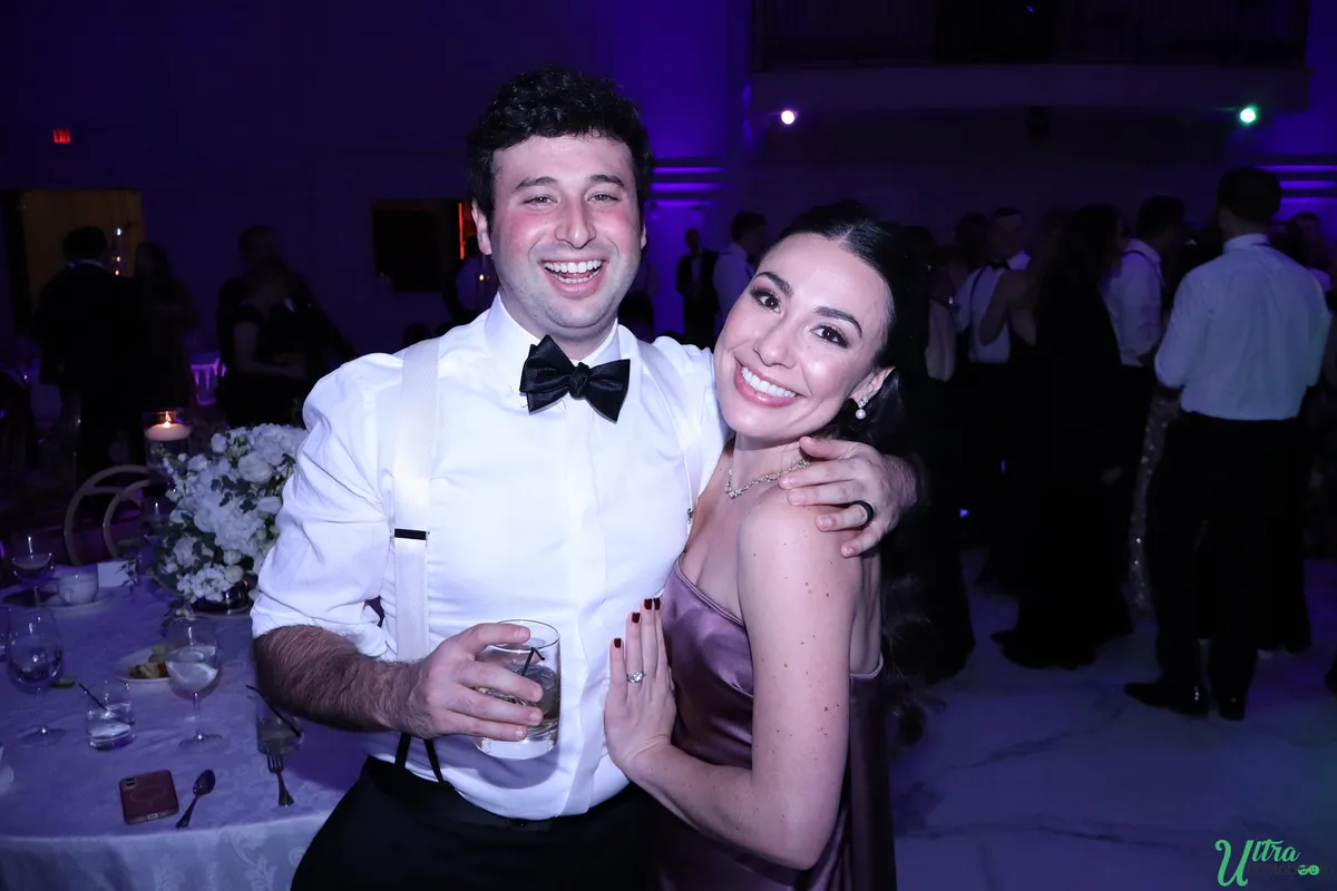 Two smiling wedding guests posing beside reception tables