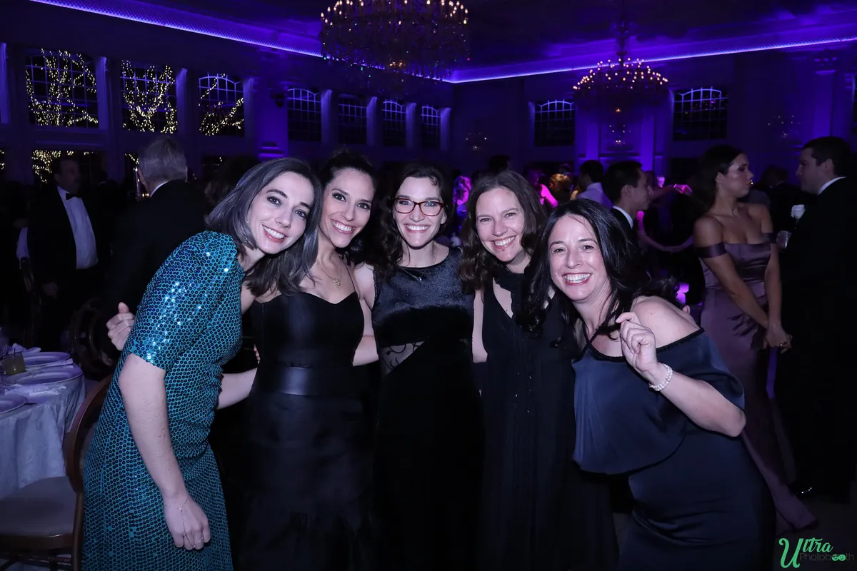 Five wedding guests posing together under purple reception lighting