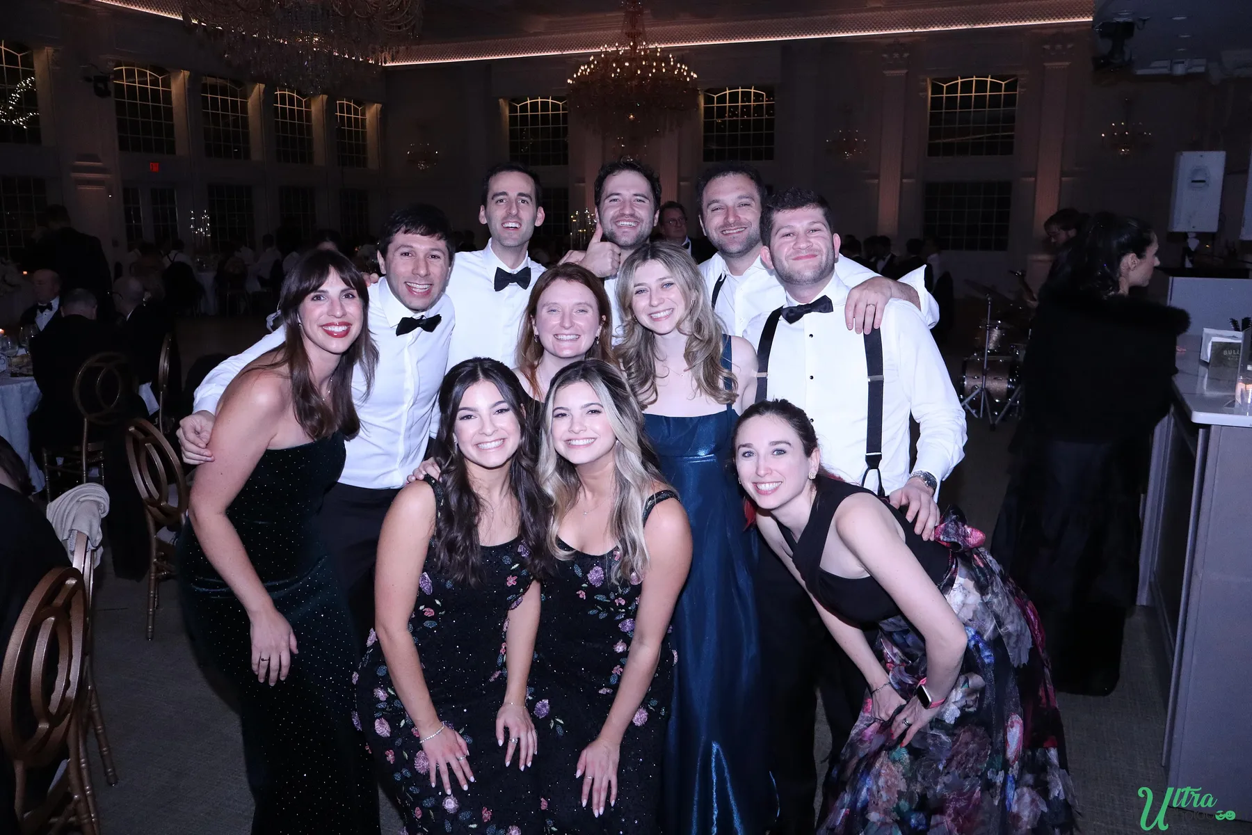 Wedding guests gathering for a group photo in a reception ballroom
